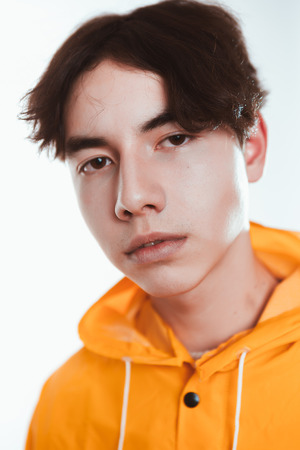 portrait of a teen guy in a yellow raincoat brunette in the studio.の写真素材