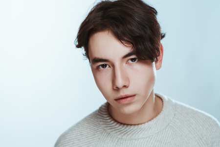 Studio portrait young man in grey sweater on white background.の写真素材