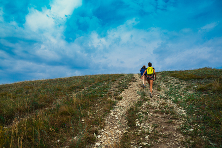 Two young girls climb into the mountains.の写真素材