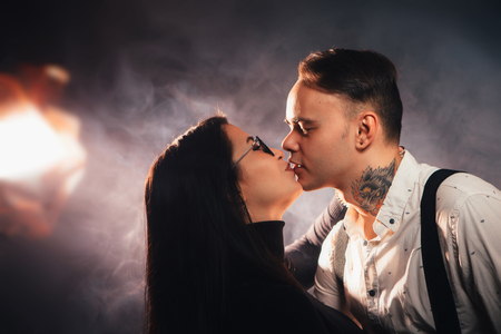 Couple in fashionable clothes on a dark smoky background.の写真素材