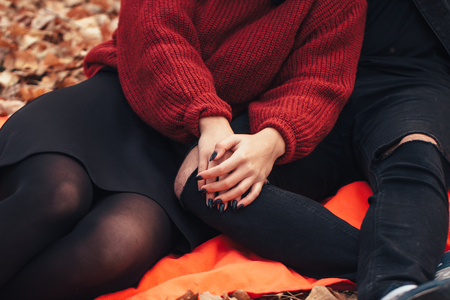 young man and young woman are sitting on a plaid in an autumn forest.の写真素材