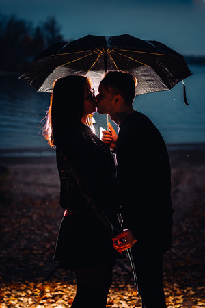 young man and woman under an umbrella and rain.の写真素材