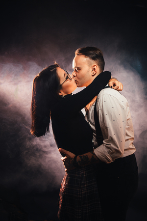 Couple in fashionable clothes on a dark smoky background.の写真素材