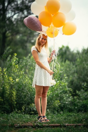 young girl with balloons on nature background.の写真素材