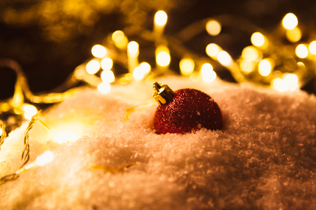 red Christmas ball and luminous garland on the snow.の写真素材