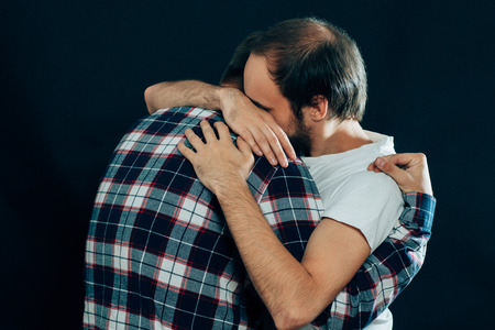 two guys hugging on a dark background.の写真素材