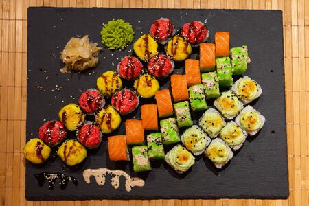 Set of rolls on a black plate with wasabi and ginger.の写真素材