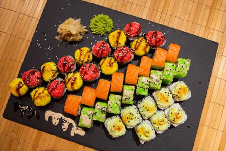 Set of rolls on a black plate with wasabi and ginger.の写真素材