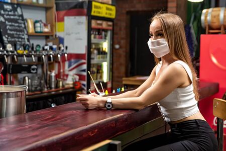 girl in a medical mask in a pub. girl in a restaurant. girl at the barの写真素材