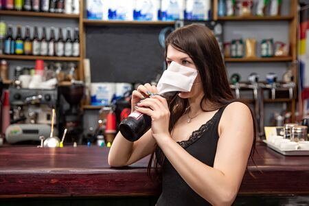 girls in medical masks drink cocktails.  girl in a medical mask is resting in a pub. girl in a medical mask in a pubの写真素材