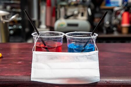 two plastic cups and a medical mask on the barの写真素材