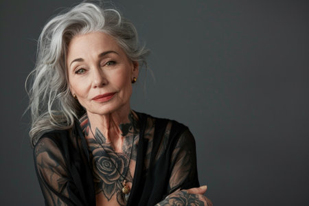 Aging with ink: elderly woman proudly poses with tattoo, showing timeless style and individuality, challenging stereotypes and embracing personal expression through body art.の素材