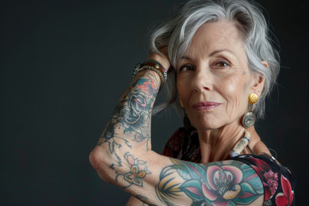 Aging with ink: elderly woman proudly poses with tattoo, showing timeless style and individuality, challenging stereotypes and embracing personal expression through body art.の素材