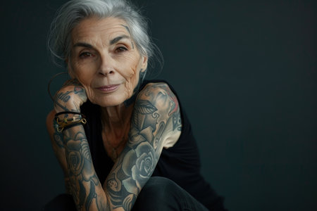 Aging with ink: elderly woman proudly poses with tattoo, showing timeless style and individuality, challenging stereotypes and embracing personal expression through body art.の素材