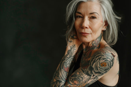 Aging with ink: elderly woman proudly poses with tattoo, showing timeless style and individuality, challenging stereotypes and embracing personal expression through body art.の素材