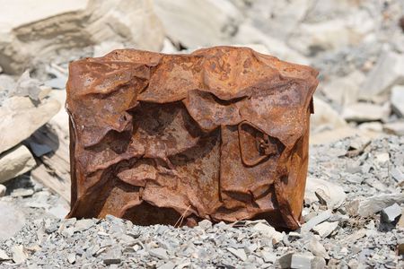 Rusted and crumpled barrel on the rocksの写真素材