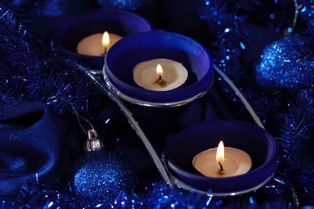 Blue candlestick and christmas decorations on the blue draperies. Narrow depth of field.の写真素材