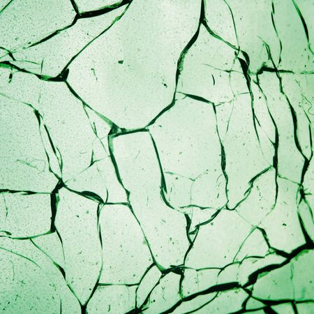 Cracked glass. Old and dusty. Close-up. Narrow depth of field. Green color.