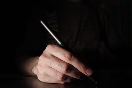 Pen in the male hand. Dark background.の写真素材