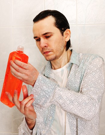 Man wearing to the white shirt are washing himself with household chemical goods.の写真素材