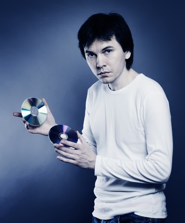 Man wearing to white long sleeves shirt are posing in the studio. With CD and DVD disk in the hands. Blue tint.の写真素材