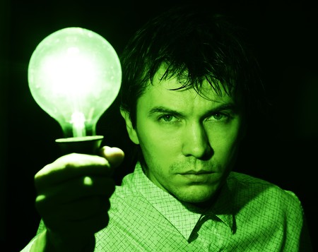 Man with electric bulb in the hand in the dark room. Green tint.の写真素材