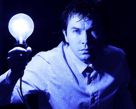 Man with electric bulb in the hand in the dark room. Blue tint.の写真素材