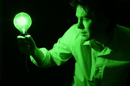 Man with electric bulb in the hand in the dark room. Green tint.の写真素材