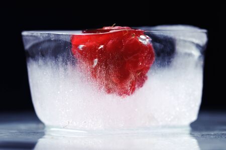Raspberry frozen in the ice cube. Black background.の写真素材