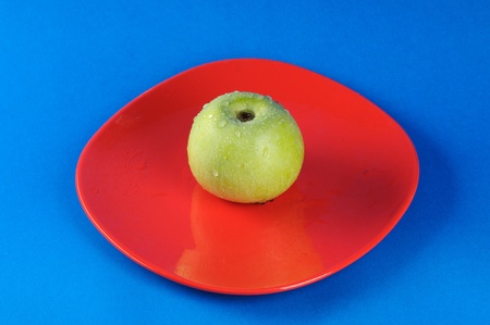 Big green apple on the red ceramic plate.の写真素材