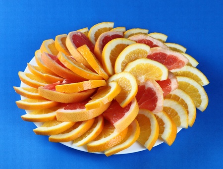 Citrus slices on the green ceramic plate. Blue background.の写真素材