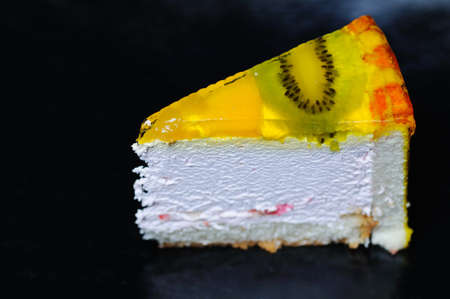 Piece of kiwi cake on the black background. Narrow depth of field.の写真素材