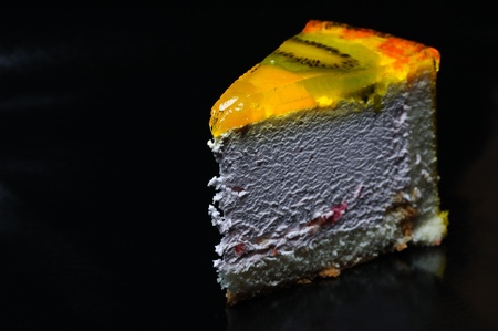 Piece of kiwi cake on the black background. Narrow depth of field.
