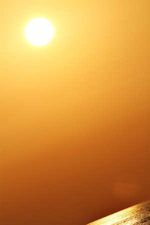 Golden sun over golden water in golden sky の写真素材