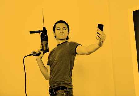 Man with hammer drill in hands. He is making selfie in time of starting of home renovation.の写真素材