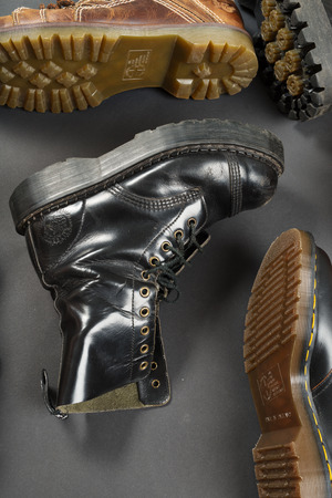 LONDON, ENGLAND - FEBRUARY 4, 2016: Old-fashioned and worn boots on gray background. Classic Dr. Martens models and classic Grinders models.のeditorial素材