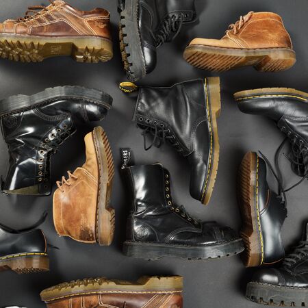 LONDON, ENGLAND - FEBRUARY 4, 2016: Old-fashioned and worn boots on gray background. Classic Dr. Martens models and classic Grinders models.のeditorial素材