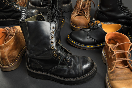 LONDON, ENGLAND - FEBRUARY 4, 2016: Old-fashioned and worn boots on gray background. Classic Dr. Martens models and classic Grinders models.のeditorial素材