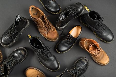 LONDON, ENGLAND - FEBRUARY 4, 2016: Old-fashioned and worn boots on gray background. Classic Dr. Martens models and classic Grinders models.のeditorial素材