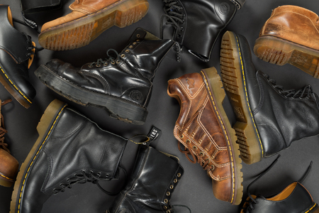 LONDON, ENGLAND - FEBRUARY 4, 2016: Old-fashioned and worn boots on gray background. Classic Dr. Martens models and classic Grinders models.のeditorial素材