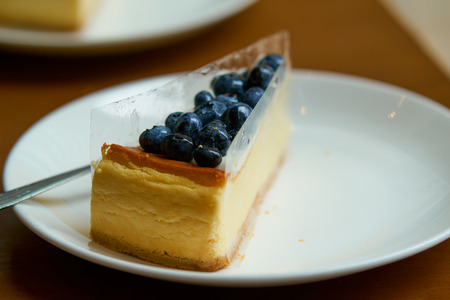 Blueberry cheesecake wrapped with plastic membrane transparent edge tape on white plate.の写真素材