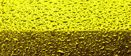 Water drops on the glass. Yellow background. Close-up.