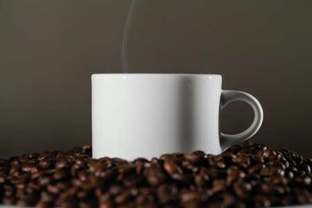 White Cup on The Table With Beans Roasted Coffee. Close-upの写真素材