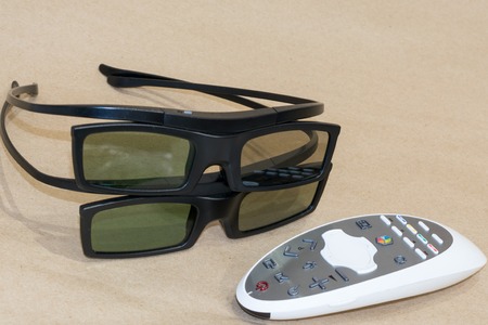 TV remote control and two pairs of 3D glasses on craftool backgroundの写真素材