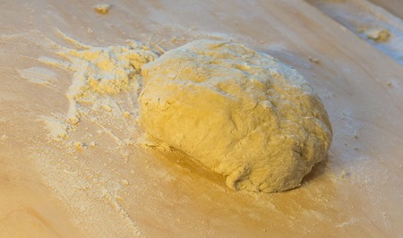 Ball of pizza dough on a rustic wooden background with dusting of flour. Preparing with their handsの写真素材