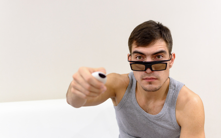 young man in 3D glasses at home on a white sofaの写真素材
