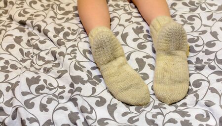 white wool socks on female feet in bedの写真素材