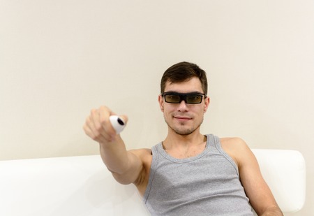 young man in 3D glasses at home on a white sofa