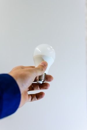 Hand holding light bulb on a gray background