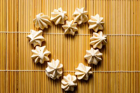 tasty of meringues on wooden background, symbol heartの写真素材